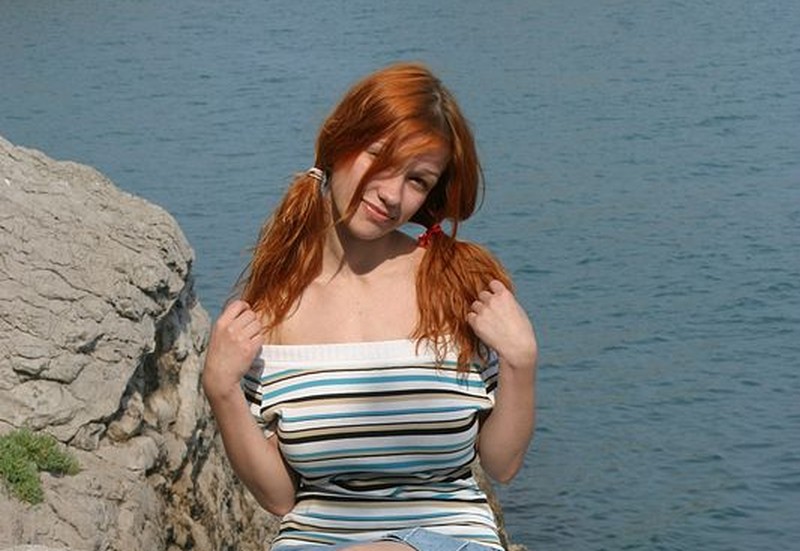 Mooie vrouw met rood haar en grote tieten, bij de zee