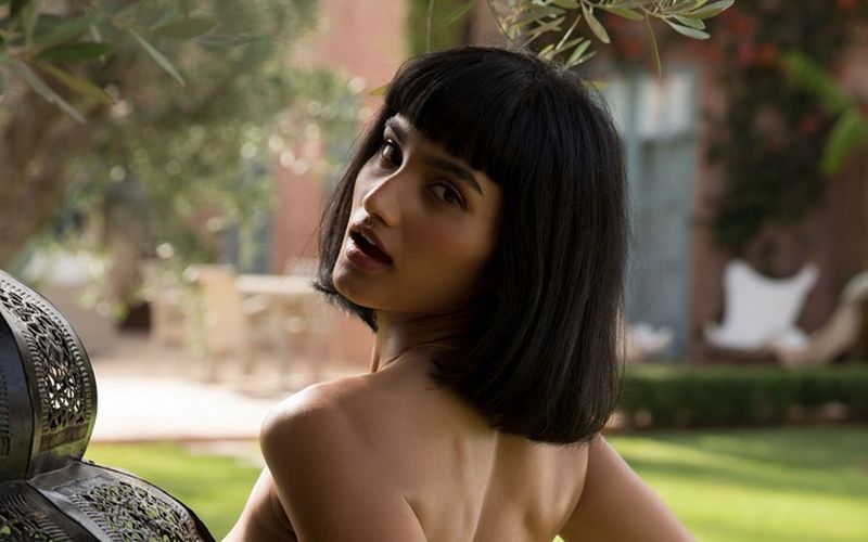 Mooie exotische vrouw, grote borsten, gaat bloot in de tuin