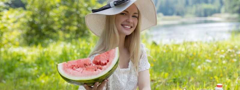 Blonde tiener eet graag buiten een watermeloen op, als ze naakt is