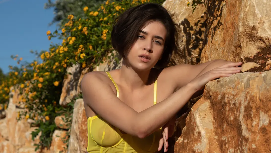 Een naakte hete vrouw leunt tegen stenen